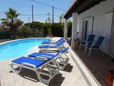 a row of lounge chairs next to a swimming pool at Casa Brisa Suave in Aljezur