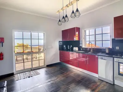 a large kitchen with red cabinets and windows at Casa DaSa by LovelyStay in Salão